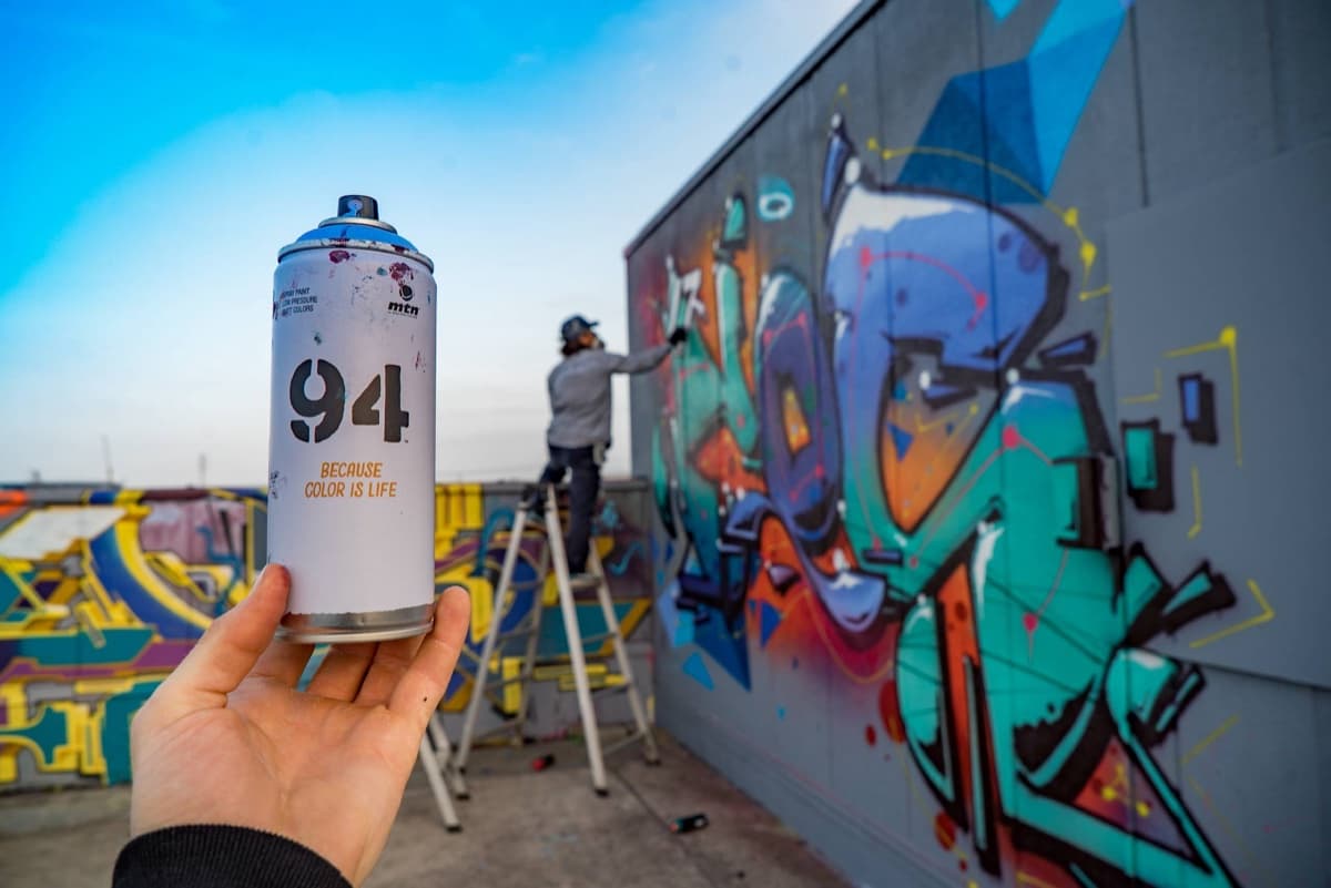 Aerosol Montana Colors MTN 94 frente a un mural urbano